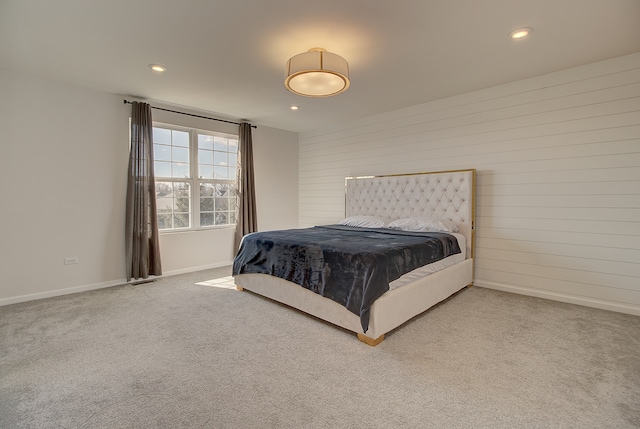 carpeted bedroom with wood walls, baseboards, and recessed lighting