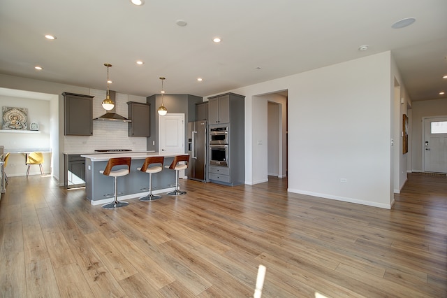 kitchen featuring a center island, stainless steel appliances, light wood-style flooring, decorative backsplash, and gray cabinetry