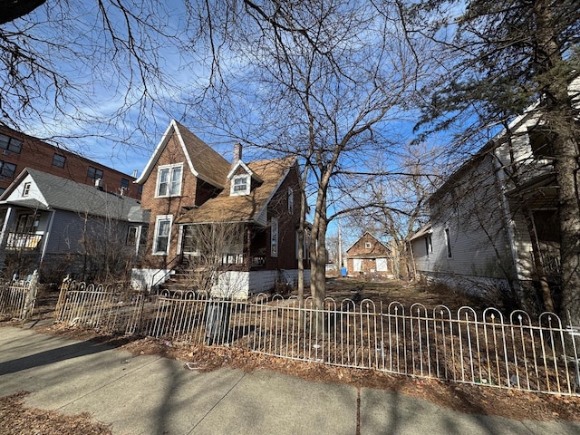 view of front of house with a fenced front yard, brick siding, and a chimney