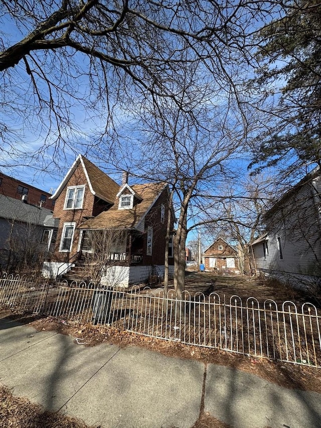 view of front facade with a fenced front yard, brick siding, and a chimney