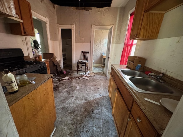 kitchen with brown cabinets, a sink, and black range with gas stovetop