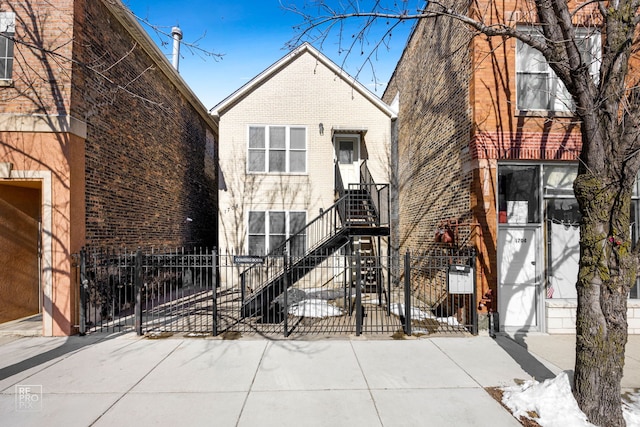 view of front facade featuring a fenced front yard, stairs, a gate, and brick siding