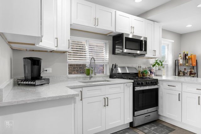 kitchen featuring recessed lighting, a sink, white cabinetry, appliances with stainless steel finishes, and light stone countertops