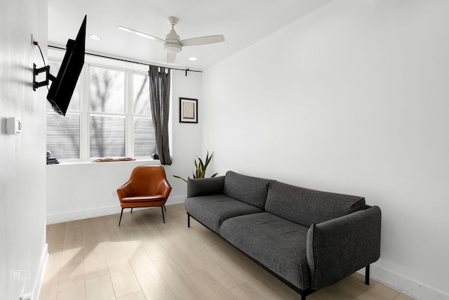 living room with wood finished floors, a ceiling fan, and baseboards