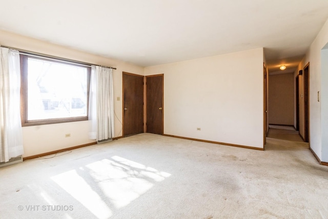 empty room with baseboards and light carpet