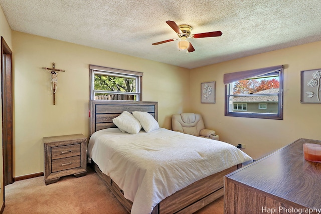 bedroom featuring light carpet, a textured ceiling, a ceiling fan, and baseboards