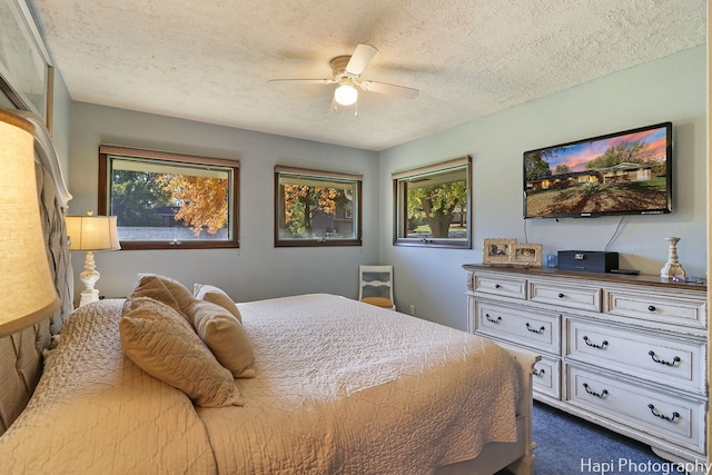 bedroom with ceiling fan, dark carpet, and a textured ceiling