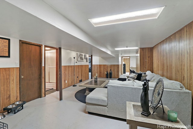 living room with finished concrete flooring, wainscoting, and wooden walls