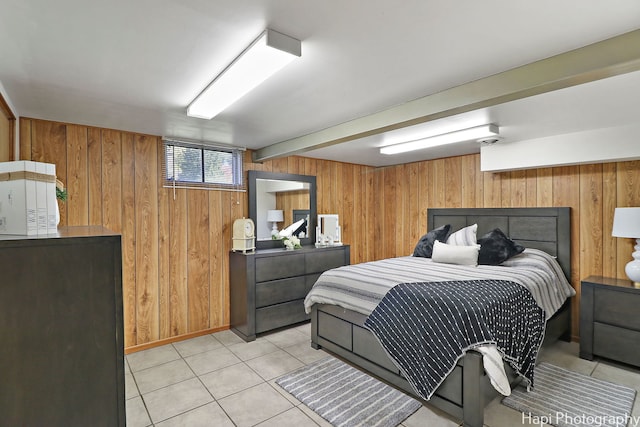 bedroom featuring light tile patterned floors and wooden walls