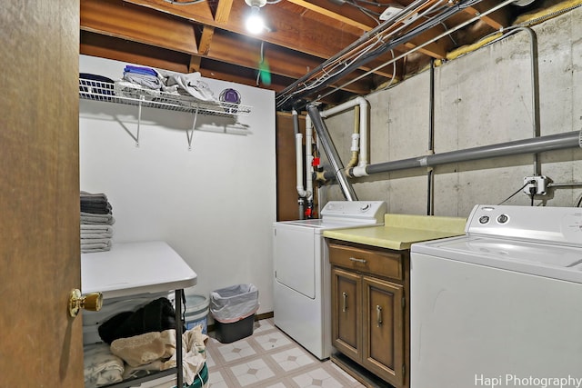 clothes washing area featuring cabinet space, washer and clothes dryer, and light floors