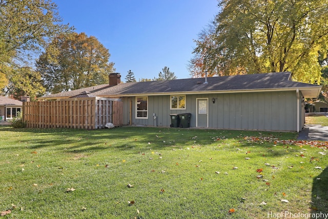 back of house featuring a chimney, fence, and a lawn