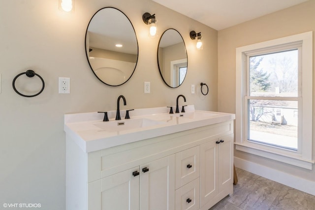 bathroom featuring a sink, baseboards, and double vanity