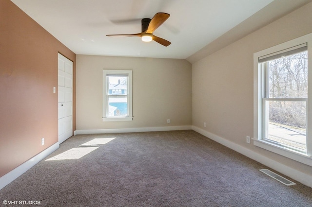 spare room with carpet floors, visible vents, ceiling fan, and baseboards