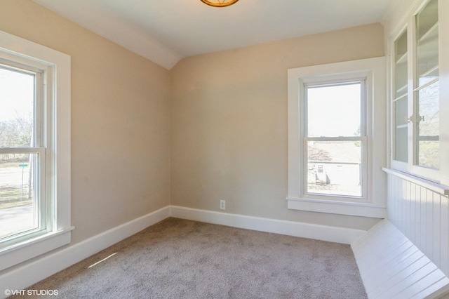 spare room featuring carpet flooring, vaulted ceiling, and baseboards