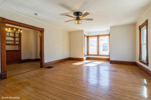 spare room with visible vents, ceiling fan, baseboards, and wood finished floors