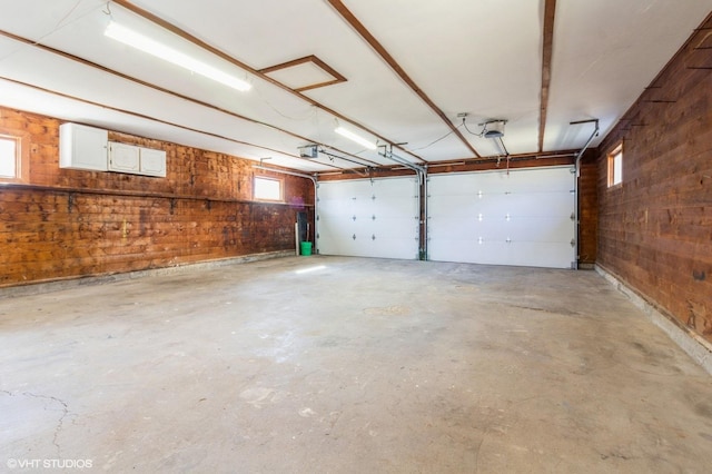 garage featuring a garage door opener and wooden walls