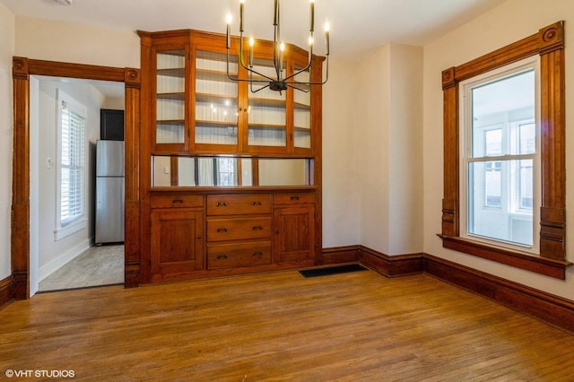 unfurnished dining area with plenty of natural light, wood finished floors, and baseboards