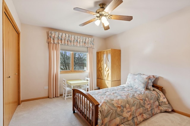 bedroom featuring baseboards, ceiling fan, a closet, and light colored carpet