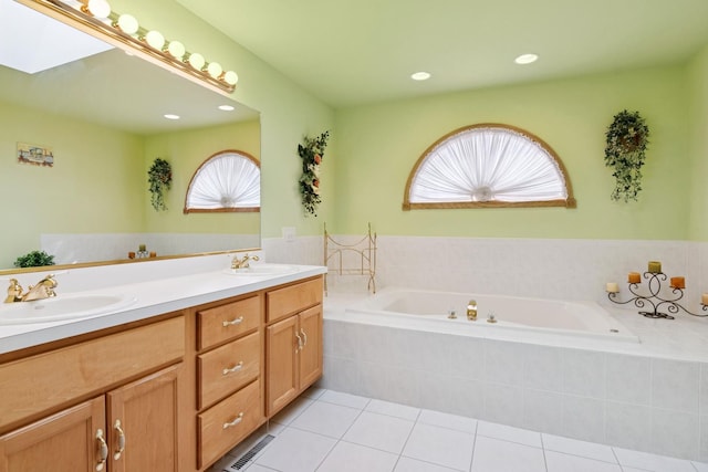 full bathroom with a bath, a skylight, a sink, and tile patterned floors