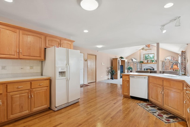 kitchen featuring white appliances, tasteful backsplash, lofted ceiling, light wood-type flooring, and a sink