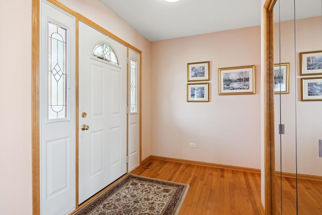 foyer entrance with baseboards, plenty of natural light, and light wood finished floors