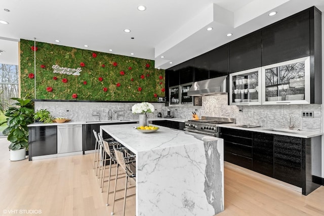 kitchen with appliances with stainless steel finishes, a sink, modern cabinets, dark cabinets, and extractor fan