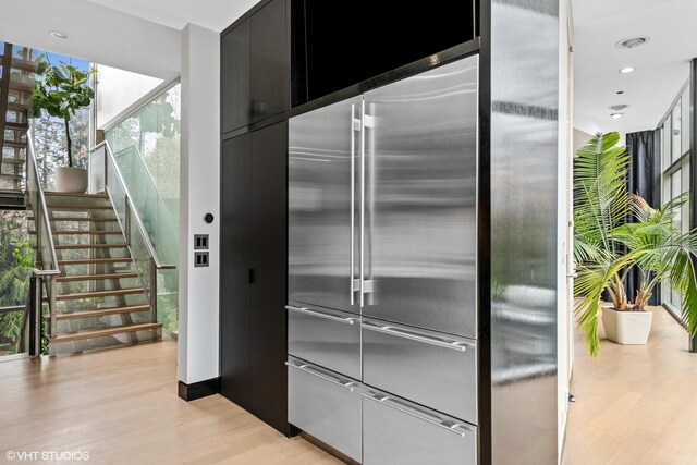 kitchen with stainless steel built in fridge, dark cabinetry, floor to ceiling windows, light wood finished floors, and modern cabinets