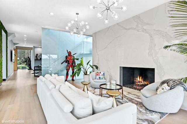 living area with a premium fireplace, recessed lighting, wood finished floors, and a notable chandelier