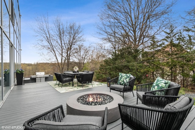 wooden terrace featuring an outdoor kitchen and an outdoor living space with a fire pit