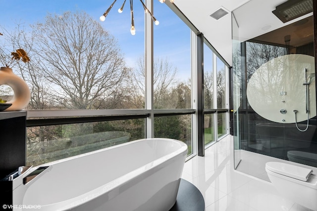 full bath featuring a freestanding tub, visible vents, and a wealth of natural light