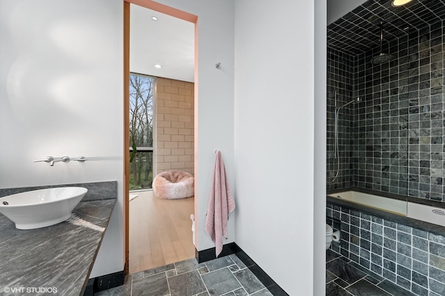 bathroom with tiled shower / bath, vanity, and baseboards