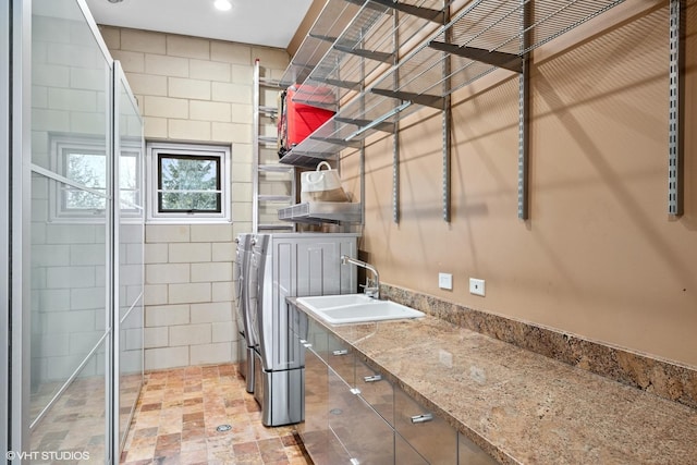 clothes washing area with recessed lighting, laundry area, a sink, and washing machine and clothes dryer