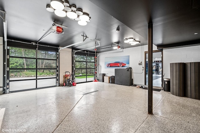 garage featuring concrete block wall and a garage door opener