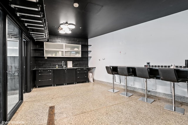 kitchen with visible vents, dark cabinets, speckled floor, open shelves, and a sink