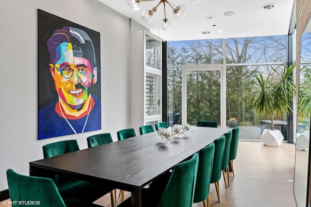 dining space with an inviting chandelier, a wall of windows, and wood finished floors