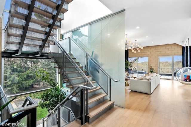 staircase with recessed lighting, wood finished floors, and an inviting chandelier