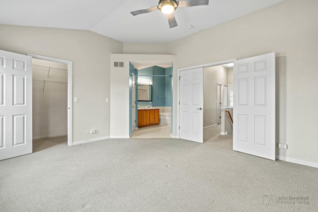 unfurnished bedroom featuring baseboards, visible vents, vaulted ceiling, and light colored carpet