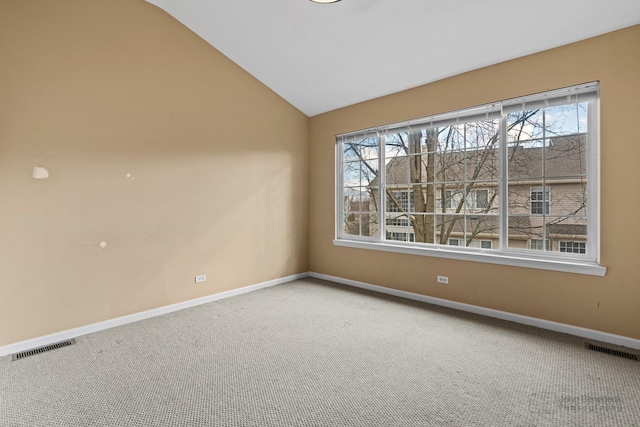 empty room with carpet, a healthy amount of sunlight, visible vents, and lofted ceiling