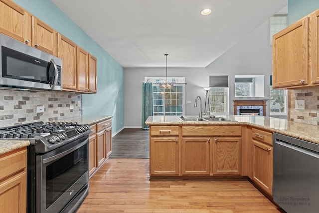 kitchen with decorative backsplash, light wood-style flooring, a peninsula, stainless steel appliances, and a sink