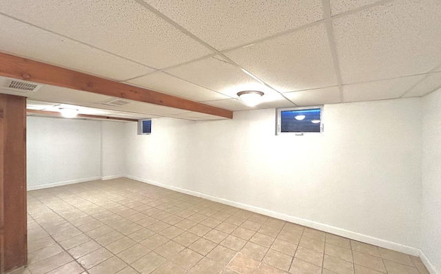 finished below grade area featuring visible vents, baseboards, and a drop ceiling