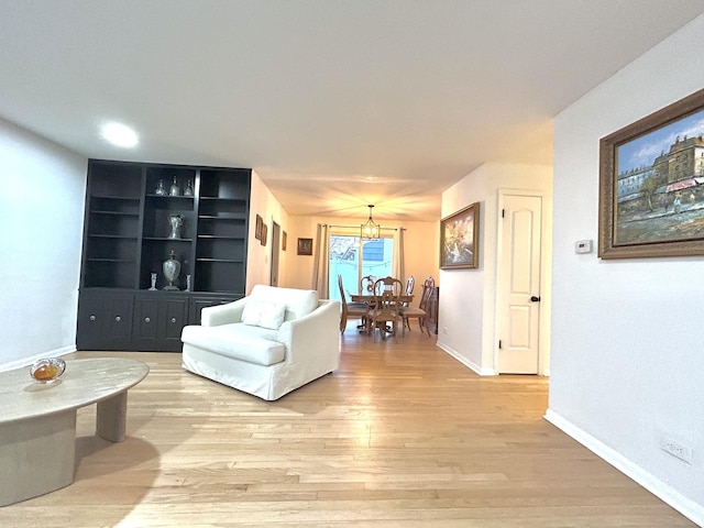 living room featuring built in features, baseboards, and light wood finished floors