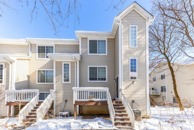 snow covered house with a deck and stairway