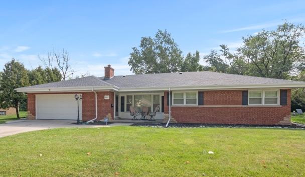 ranch-style house with concrete driveway, a front lawn, an attached garage, and brick siding