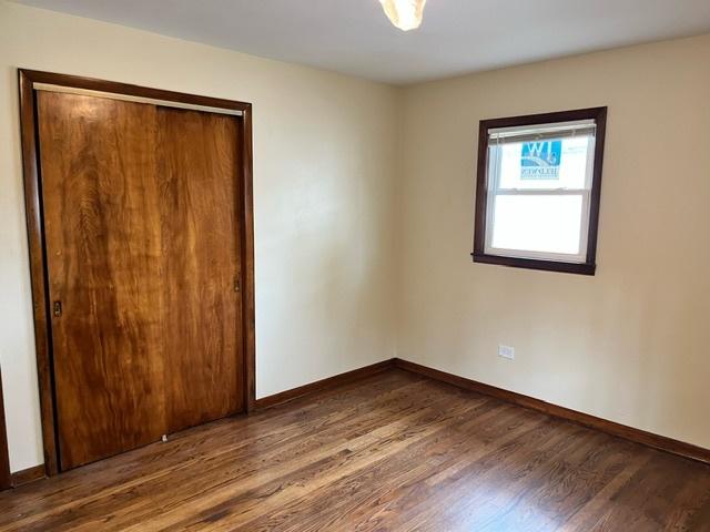 unfurnished bedroom with a closet, baseboards, and dark wood-type flooring