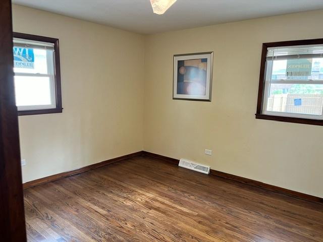 empty room with visible vents, dark wood finished floors, and baseboards