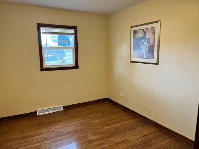 empty room featuring visible vents, dark wood finished floors, and baseboards