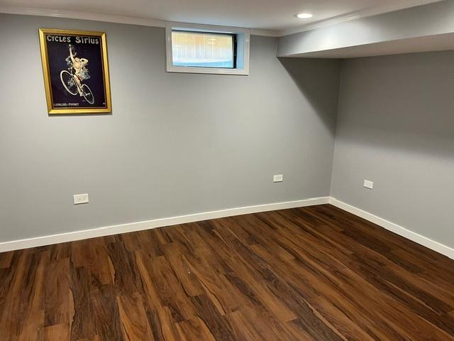 below grade area featuring ornamental molding, recessed lighting, dark wood-style flooring, and baseboards