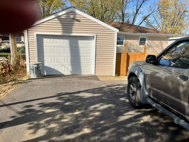 detached garage featuring aphalt driveway and fence