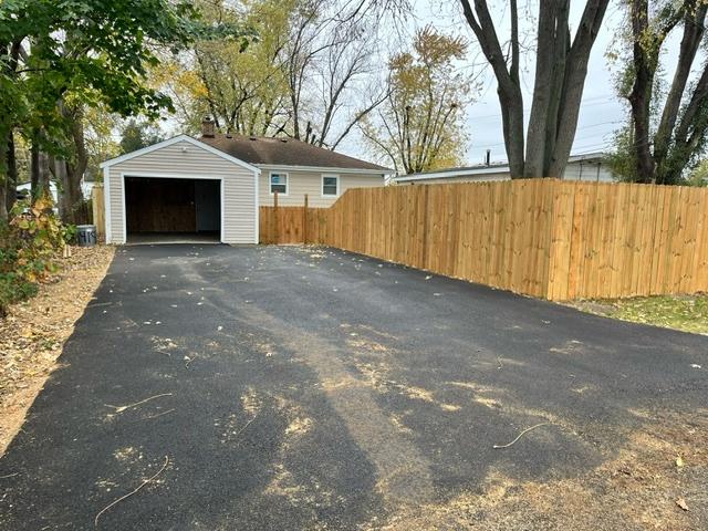 detached garage featuring driveway and fence