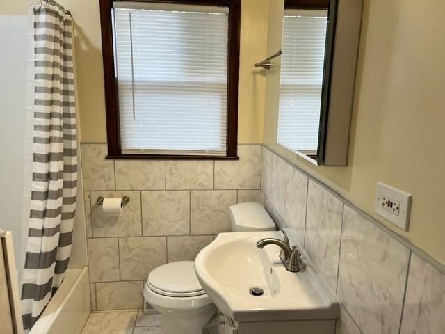 full bathroom featuring toilet, tile patterned flooring, tile walls, and vanity